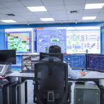 Operador trabalha em uma moderna sala de controle, monitorando sistemas tecnológicos.