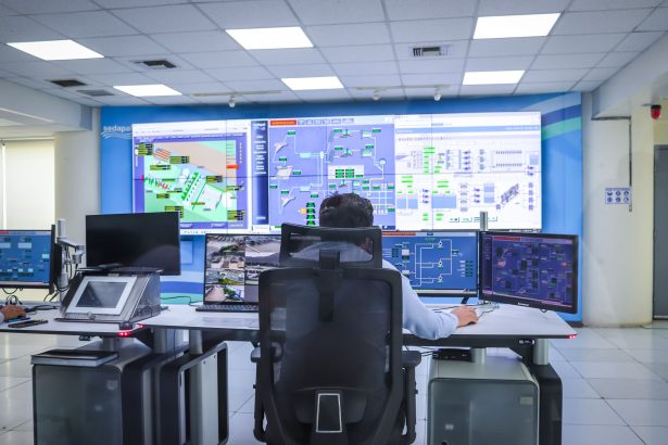 Operador trabalha em uma moderna sala de controle, monitorando sistemas tecnológicos.